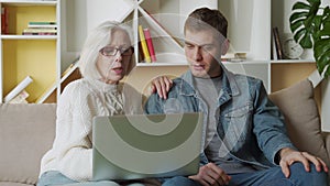 Man teaching his mother using laptop at home, technology concept.