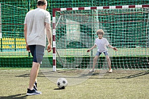 Man teaching his son how to play soccer outdoors