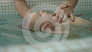 Man teaching his son to swim on the back in the child pool