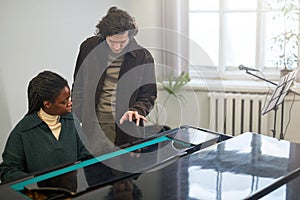 Man teaching student to play the piano