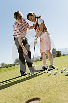 Man teaching teenage girl how to putt