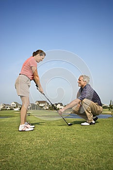 Man teaching woman golf