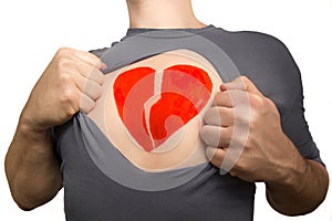 Man tearing apart grey t-shirt. Broken red heart painted on his