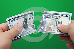 Man tearing dollars on green background
