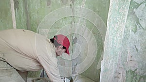 Man is tearing huge piece of wallpaper from the wall during house renovation process in slowmo