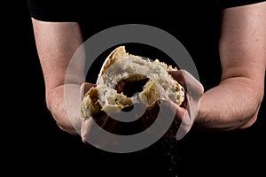 Man tearing a piece of bread in the middle of bread to share. Helping hands concept of sharing.