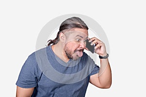A man teases and ridicules someone over the phone. Sticking out his tongue out of habit. Communication concept photo