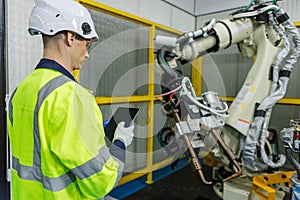 Man technician engineer using tablet control automation robotics at industrial modern factory. Male worker checking automation