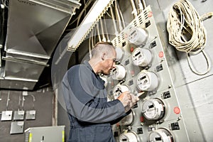 Man Technician servicing at work on electric room