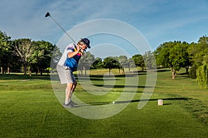 Man teeing off in the tee box, playing golf