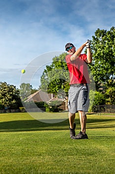 Man teeing off in the tee box, playing golf