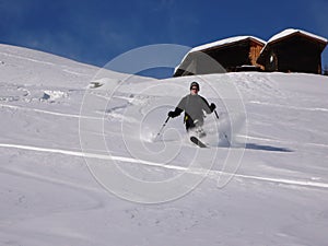 Man teelemark skiing in the Swiss backcountry in deep winter and fresh powder on a beautiful day