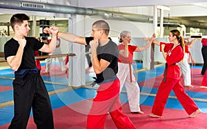 Man and teenage boy sparring during group karate training
