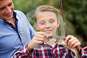 Man with teenager boy releasing fish from hook