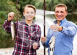 Man with teenager boy showing catch fish