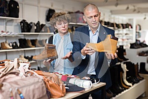 Man and teenager looking for demi-season mens shoes in store