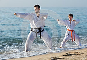 man and teenager show karate poses