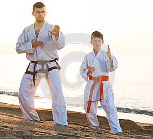 Man and teenager in uniform doing exercises