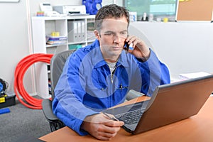 Man on telephone in front computer