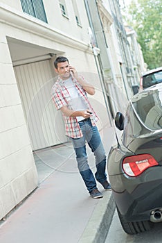 Man on telephone unlocking car door with central locking device