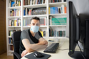 Man teleworking at home with mask