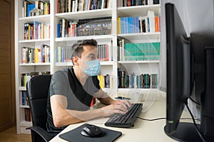 Man teleworking at home with mask