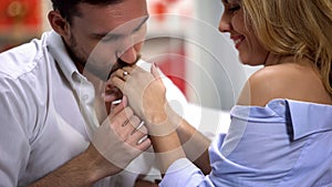 Man tenderly kissing womans hand with engagement ring, proposal marriage, love