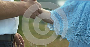 The man is tenderly taking the woman hand and hugging her in the golden field.