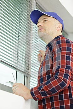 Man testing blinds on windows