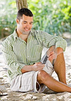 Man text messaging on cell phone at beach
