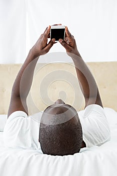 Man text messaging on mobile phone in bedroom