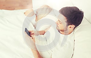 Man texting message while woman is sleeping in bed