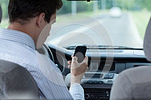 Man texting on mobile phone during driving a car