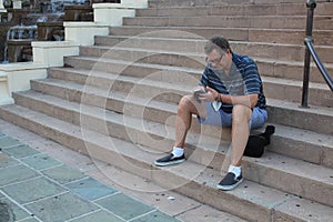Man Texts on his Mobile Cellular Phone on Steps in a City