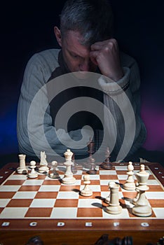 Man thinking behind chessboard.
