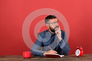 Man with thinking face sits at wooden table