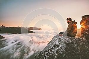 Man thinking sitting alone on cliff edge mountain top