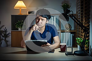 man thinking while using tablet at night