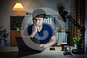 man thinking and working with laptop at night