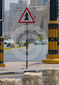 Man in thobe crosswalk sign on busy street photo