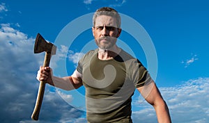 man threaten with axe. angry man hold ax. brutal man on sky background