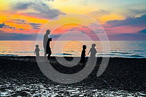 Man and three children silhouetted at sunset on the shoreline of Lake Michigan near the Indiana Dunes State Park