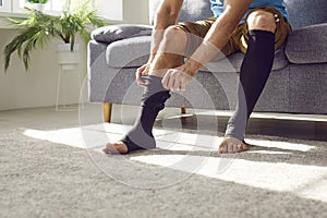 Man with thrombosis or varicose disease puts on stretchable compression stockings