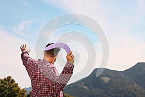 Man throwing boomerang in mountains on sunny day, back view. Space for text