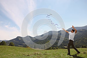 Man throwing boomerang in mountains on sunny day. Space for text