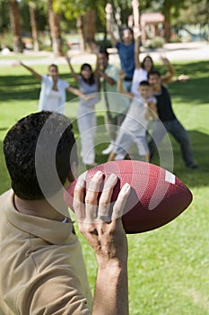 Man throwing football to group of people back view.