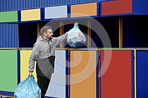 Man throwing garbage into bin at recycling point outdoors