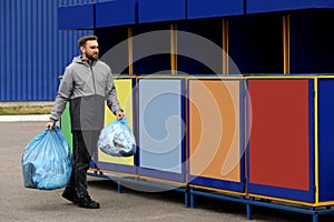 Man throwing garbage at recycling point outdoors