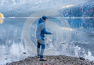 A man is throwing a little stone in the lake