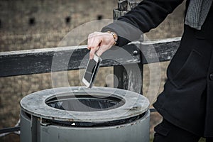 Man throwing phone in garbage bin